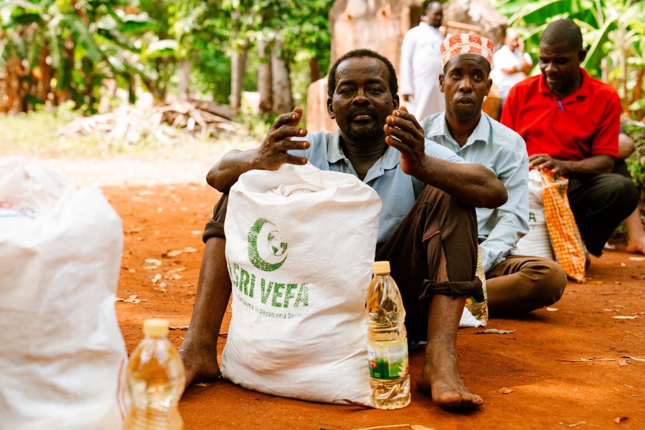 The Art of Drawing Readers In: Your attractive post title goes here People seated outdoors with bags of supplies, indicating a community gathering.
