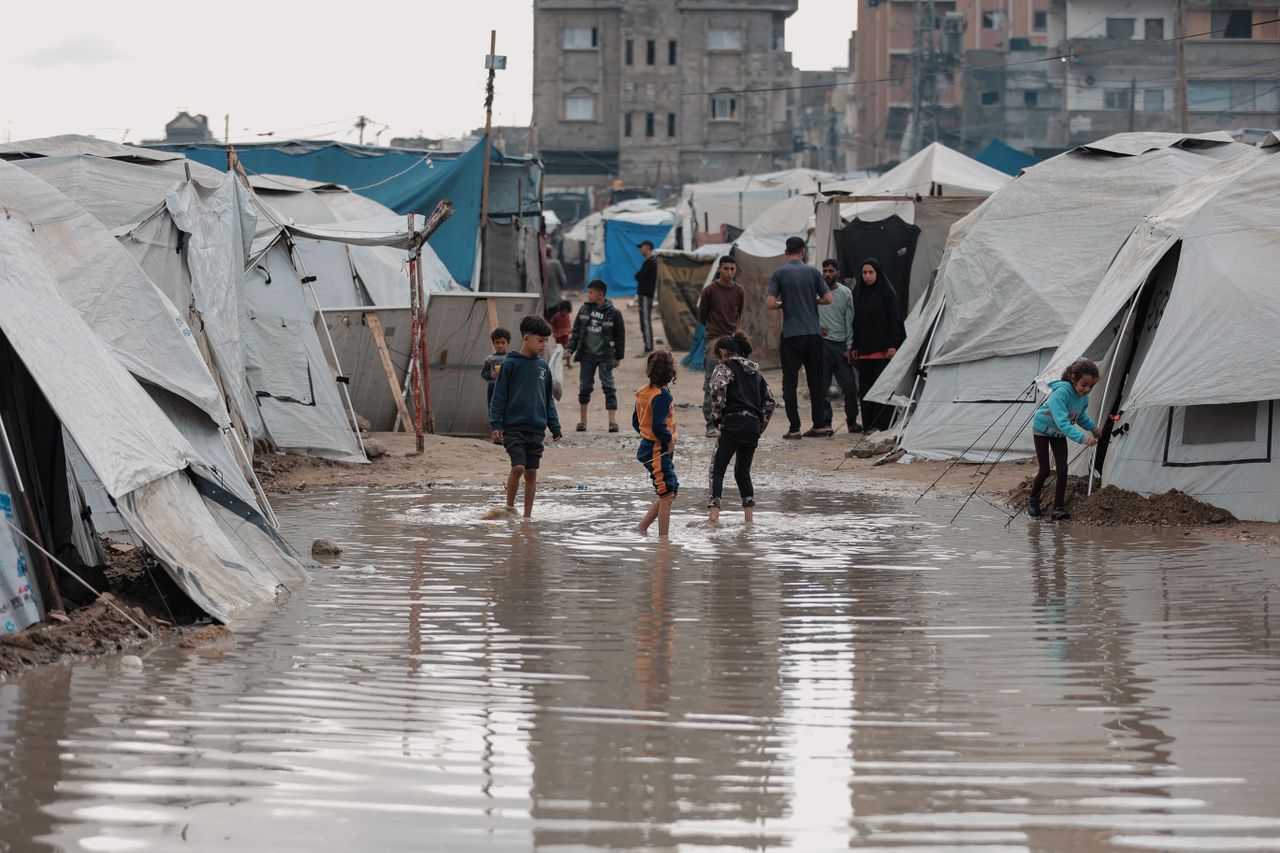 Children play in a flooded refugee camp in Gaza, reflecting resilience and daily life challenges.