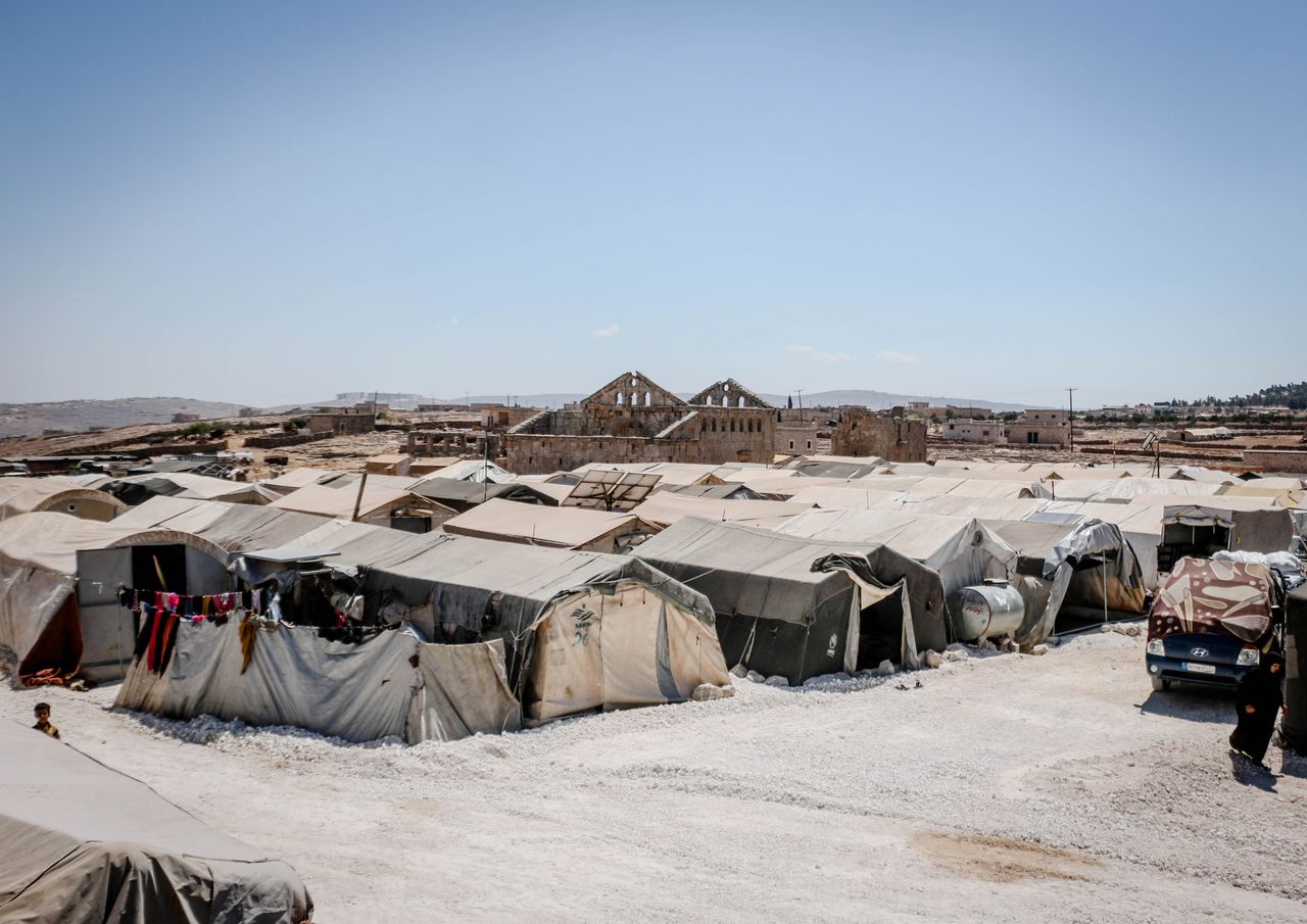 A refugee camp in Idlib, Syria, with tents under a clear blue sky, highlighting humanitarian aid efforts.